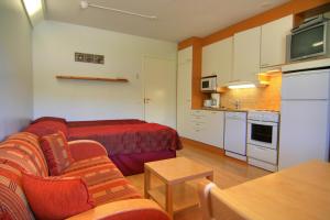 a living room with a red couch and a kitchen at Tahko Huoneistohotelli A in Tahkovuori +4 photos