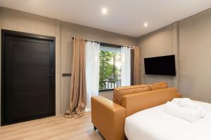 a bedroom with a bed and a couch and a television at OHASIS by OH Hotels in Bangkok