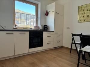 a kitchen with white cabinets and a black dishwasher at a feines Platzl in Asch