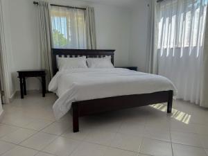 a bedroom with a large bed with white sheets at Greenpark Staycations in Athi River