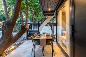 a table and chairs on a patio with a tree at OHASIS by OH Hotels in Bangkok