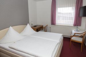 a bedroom with a large white bed and a table at Pension Der kleine Nachbar in Gotha
