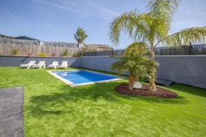 a backyard with a swimming pool and two palm trees at La Villa del Roc in Roda de Bará