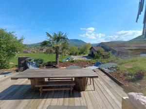 a wooden picnic table on a deck with a palm tree at Ti caz prairie in Marnoz