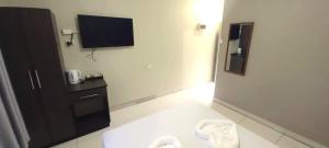 a bathroom with a tv on the wall next to a room at Red Palm Hotel in Suva
