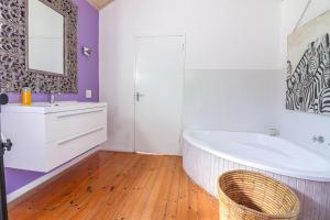a bathroom with a tub and a sink and a mirror at Airconditioned Apartment for 3 guests. in Hermanus
