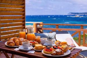 a table with breakfast food on a table with the ocean at B&B Les Capitaineries in Bonifacio