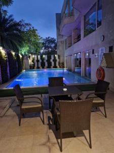 a swimming pool with tables and chairs in front of a building at Sarovar Premiere Jaipur in Jaipur