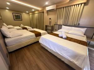 two beds in a hotel room with two bedsskirts at Cambridge Guest House in Mandaue City