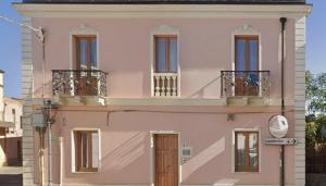 a pink house with balconies on a street at ELEGANCE GIBA Rooms in Giba