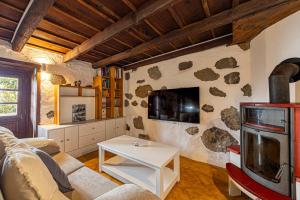 a living room with a couch and a tv at Casa Piedra y Tea in Tijarafe