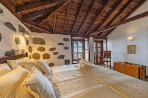 a large bed in a room with a stone wall at Casa Piedra y Tea in Tijarafe +21 photos
