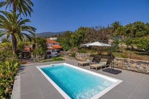 a swimming pool with two chairs and a house at Casa Piedra y Tea in Tijarafe