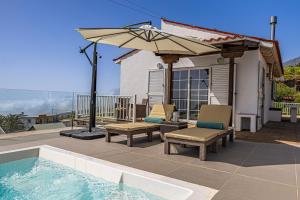 a patio with chairs and an umbrella next to a pool at Casa Yuliana in Tijarafe