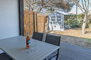 a table with wine glasses and a bottle on a porch at L'Echo des Vagues -Conciergerieland in Vieux-Boucau-les-Bains