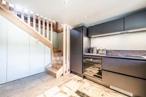 a kitchen with black cabinets and a staircase at Chalet Design Terre De Sapins in Mont-Saxonnex