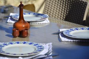 a glass table with blue and white plates and a vase at Roukouneli Traditional Stone House - Terrace & BBQ in Arménoi