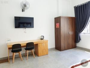 a desk with two chairs and a television on a wall at Vy An Hotel in Bảo Lộc +26 photos