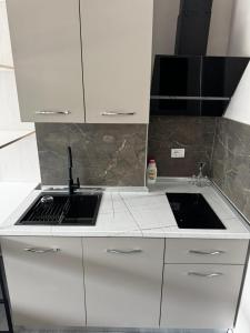 a kitchen with white cabinets and a sink at Forum View Apartments in Durrës