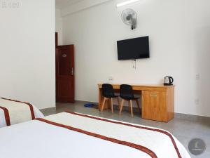 a room with two beds and a desk with a television at Vy An Hotel in Bảo Lộc