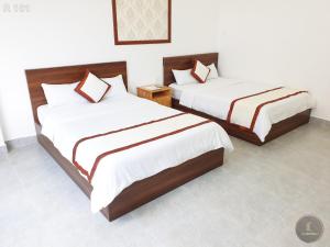 two beds in a room with white walls at Vy An Hotel in Bảo Lộc