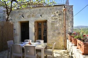 a patio with a table and chairs in front of a building at Roukouneli Traditional Stone House - Terrace & BBQ in Arménoi