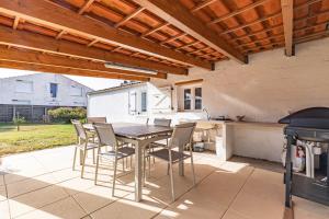 a patio with a table and chairs and a grill at Maison de vacances La Menou in Saint-Pierre-dʼOléron