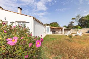 a white house with pink flowers in the yard at Maison de vacances La Menou in Saint-Pierre-dʼOléron