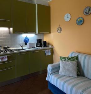 a kitchen with green cabinets and a couch in a room at Casa Luciana in Mergozzo