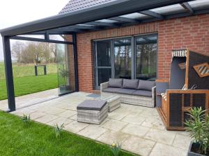 a patio with a couch under a pergola at Ferienhaus Dorie in Dornumersiel