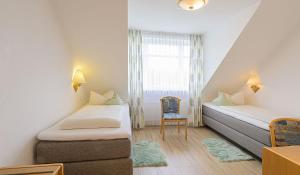 a small room with two beds and a chair at Hotel Restaurant Bergeshöhe in Mettingen