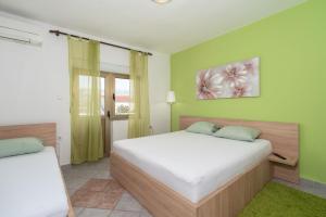 a bedroom with two beds with green walls at Apartments Zeljko in Pag