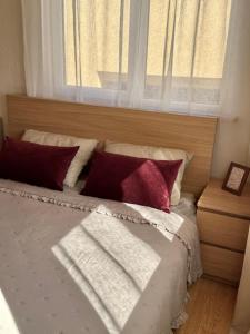 a bed with red and white pillows and a window at Malūno namai 2 in Palanga