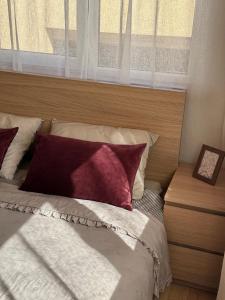 a bed with red and white pillows and a window at Malūno namai 2 in Palanga