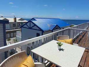 a table and chairs on a balcony with the ocean at Point Village Hotel and Self Catering in Mossel Bay