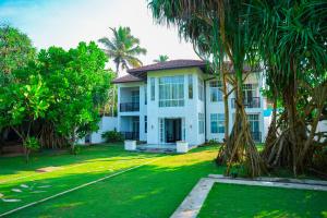 a white house with palm trees in front of it at Villa Oceana By Heritage in Hikkaduwa