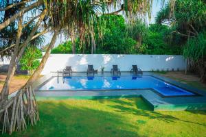 a swimming pool with chairs in a yard at Villa Oceana By Heritage in Hikkaduwa