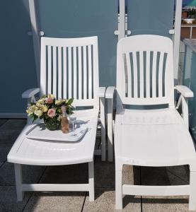 two white rocking chairs with a vase of flowers at Alte Teestube Alte Teestube 14 in Norderney