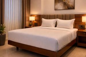 a bedroom with a large bed with white sheets at Chethan International in Bangalore
