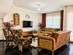 a living room with a couch and chairs and a tv at Begonville Villas Ladies Beach in Kuşadası