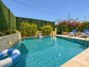 a swimming pool with blue chairs in a backyard at Begonville Villas Ladies Beach in Kuşadası
