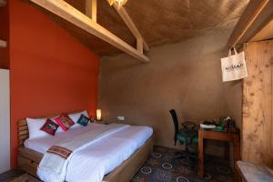 a bedroom with a bed and a table with a chair at Nomad Eco Retreat in Shimla