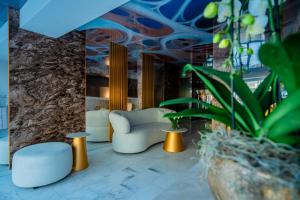 a lobby with a couch and chairs and plants at Noble Hotel by Building Stefan in Mamaia Sat/Năvodari