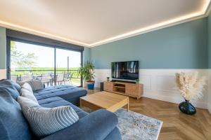 a living room with a blue couch and a tv at L'Evasion, Piscine et jacuzzi in Lescherolles