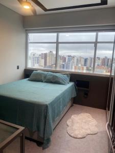 a bedroom with a bed and a large window at Studio Centro Curitiba - para ate 3 pessoad in Curitiba +18 photos