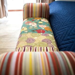 einem gestreiften Stuhl mit Blumenmuster auf einem Bett in der Unterkunft Brezza Marina B&B in Barletta