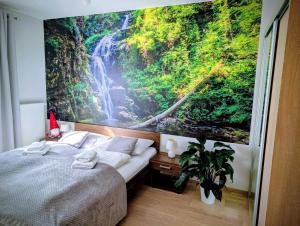 a bedroom with a large painting of a waterfall at Apartament Góry Las in Szklarska Poręba