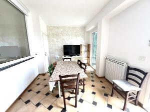a dining room with a table and chairs and a television at Appartamento Nettuno in Villa Daria a 2 Km dal mare golfo del Tigullio in Chiavari