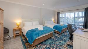 a hotel room with two beds and a table at Stonehouse on Main in Struisbaai