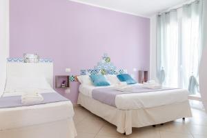 a white bedroom with two beds with blue pillows at Sterlizia Rooms in Gallipoli